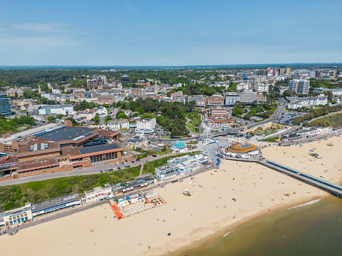 Bournemouth, UK. 22 May 2023. Bournemouth seafront with pier, conference centre, shops, cafes and people on the beach.