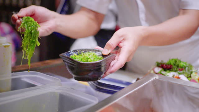 Japanese chef putting seaweed salad on a bowl at Japanese restaurant