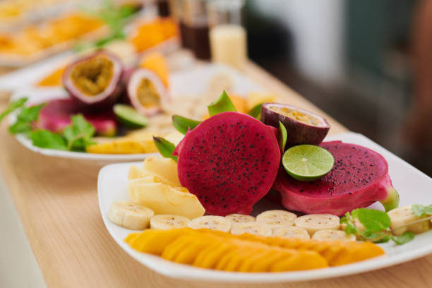 Sliced dragon fruits, bananas and mangoes on plate for customer