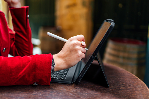 Woman using a stylus pen on a digital tablet outdoors