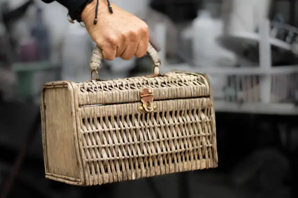 hand carrying an old wicker suitcase