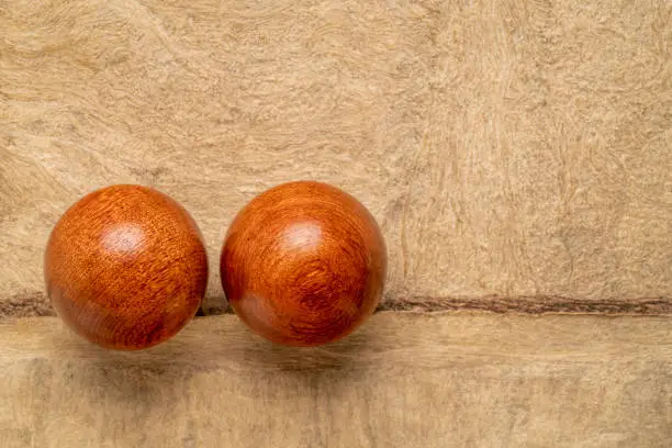 a pair of wooden Chinese medicine balls on textured paper