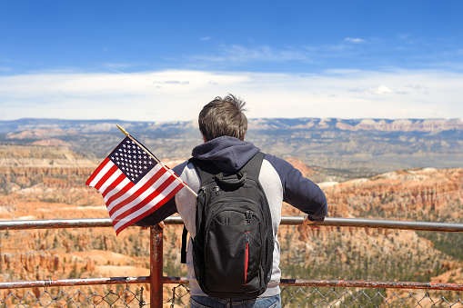 Man tourist admiring with american flag of amazing view of Bryce Canyon National Park, Utah, United States