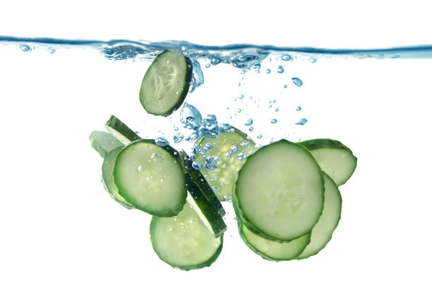 istock Slices of fresh cucumber falling into water on white background, closeup 1492704208