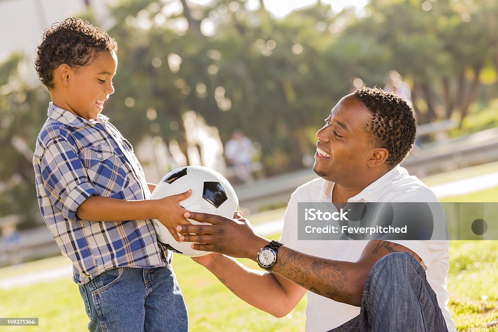 Padre mani nuovo Pallone da calcio al figlio di razza mista - Foto stock royalty-free di Calcio - Sport