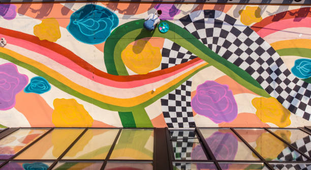 Young Latin woman artist painting sidewalk mural Young Latin woman artist painting sidewalk mural . She is dressed in casual work clothes. Exterior of public sidewalk in downtown of large North American City. Drone point of view. street art stock pictures, royalty-free photos & images