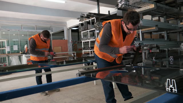 A blue-collar workers are installing cutted metal frames parts