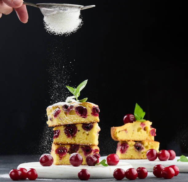istock Baked sponge cake with cherries sprinkled with powdered sugar, black background 1492718439