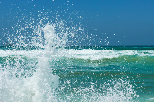 sea waves break on the rocks forming beautiful splashes of unusual shape , seascape on a warm summer day