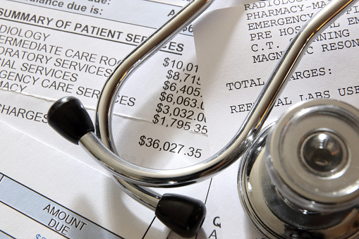 A stethoscope rests on top of a medical bill.
