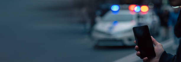 Holding a phone in front of police cars stock photo