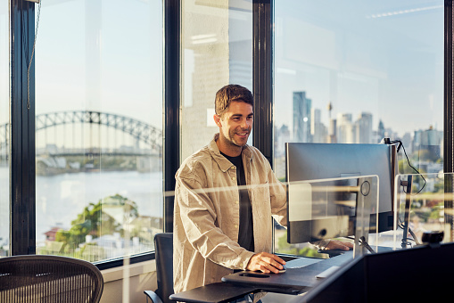 Single worker in an Australian office environment. Views of Sydney harbour and city skyline.