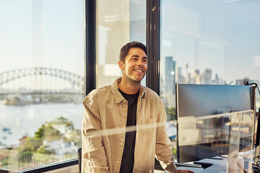 Single worker in an Australian office environment. Views of Sydney harbour and city skyline.