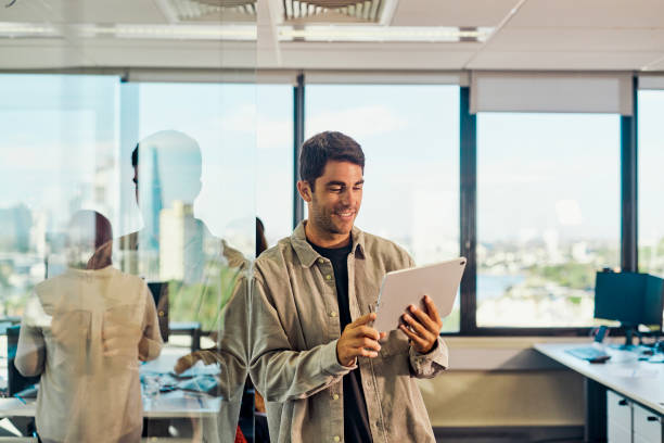 Smiling Man in a Shirt Using a Digital Tablet in the Office