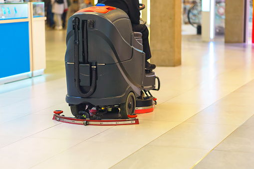 A worker in a shopping mall rides a scrubbing machine and cleans