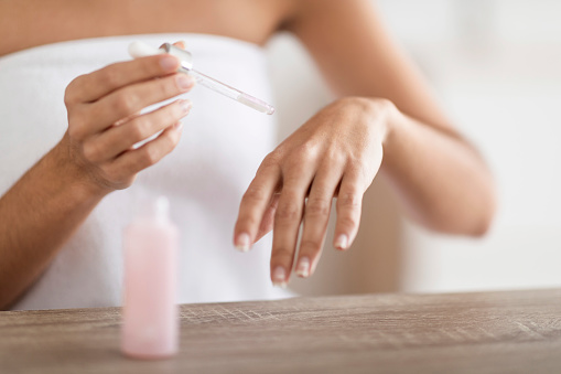 Body Care. Unrecognizable Young Woman Applying Organic Moisturising Serum On Hands Skin, Closeup Shot Of Female Pampering Herself After Bath, Making Beauty Treatments At Home, Cropped Image