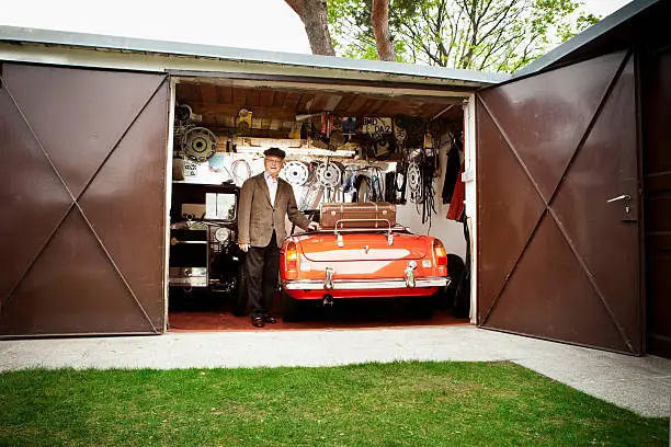 Photo of Senior man with vintage car in garage