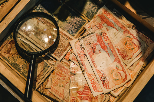 Old fashioned magnifier placed over old Indonesian money. Vintage, detective look.