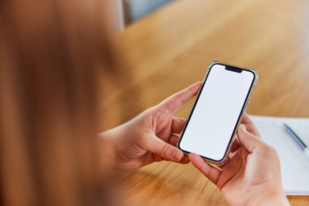 istock A close-up of a brunette holding a mobile phone with a blank white screen. 1492726391
