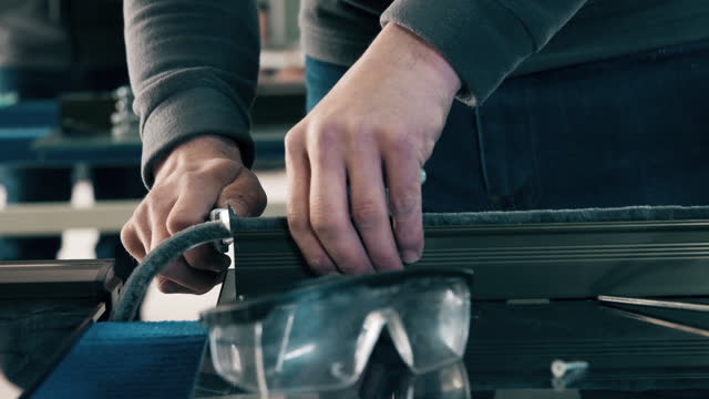 A worker is placing a long felt tube between the metal frame parts