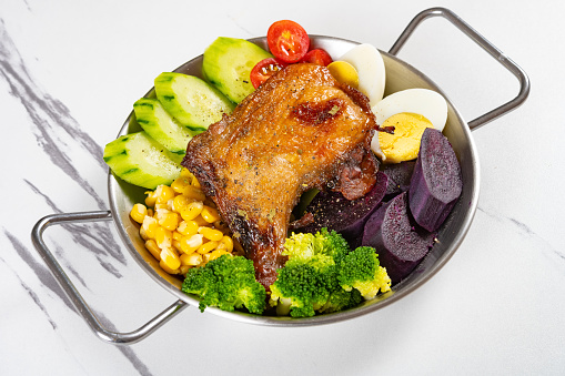 angle view healthy meal with roasted chicken leg and cucumber and eggs and broccoli and sweet potatoes and maize and cherry tomatoes