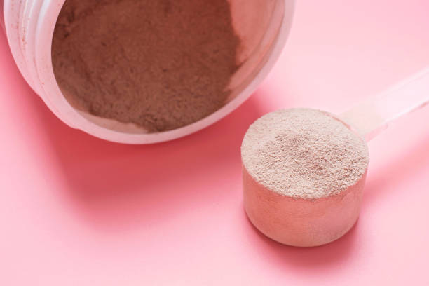 istock Chocolate protein powder in scoop and plastic jar on pink background. 1492742372