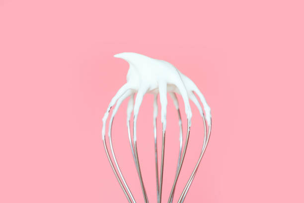 istock Whisk with whipped cream on pink background close-up. 1492744471