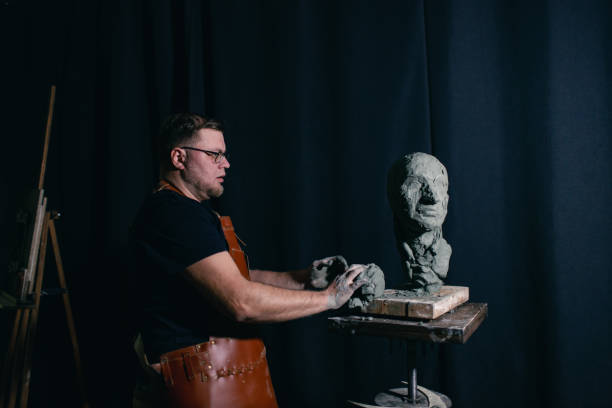 istock Man sculptor creates sculpt bust clay human woman sculpture. Statue craft creation workshop 1492753761