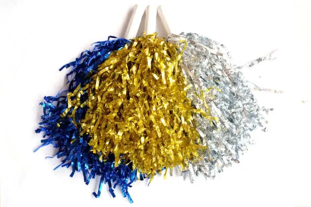 A colorful blue, silver and gold pompoms on white background