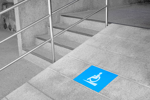 Blue disabled sign for wheelchair lane beside concrete stair