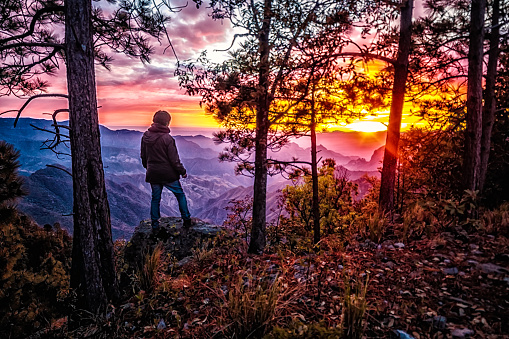 Hombre de pie frente a paisaje de la sierra madre occidental, atardecer rojo en montañas impresionantes  en bosque de durango