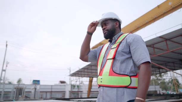 istock African American engineer or contractor or manager have leadership and expertise wearing safety uniform, standing get ready to work at real estate construction site of buildings or housing projects. Foreman or worker is working in construction industry. 1492764621