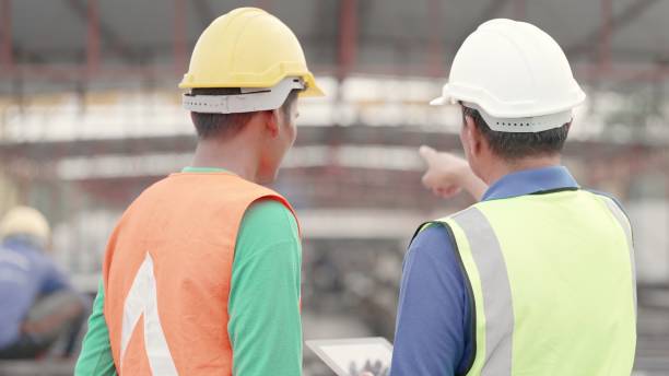 istock Foreman or worker is working in construction industry. Asian engineer or contractor and foreman have expertise, wearing safety uniform, discuss process in construction site of buildings or housing projects. Employee is working in construction industry. 1492764695