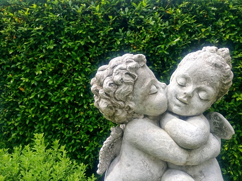 Cupid and Angel statue, Boy's statue kissing girl in garden.