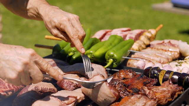 4K video of Man flipping meat on the grill at a family picnic BBQ fathers day or mothers day