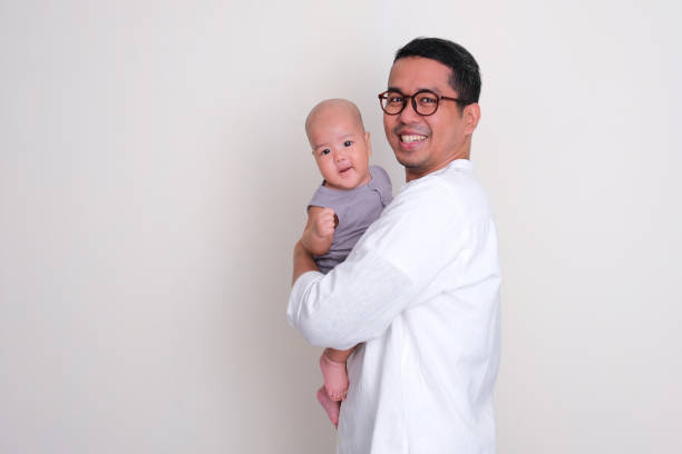 Side view of a father carrying his baby son with happy expression Side view of a father carrying his baby son with happy expression keluarga stock pictures, royalty-free photos & images