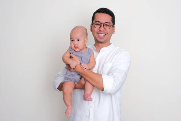A father smiling happy while holding his baby son