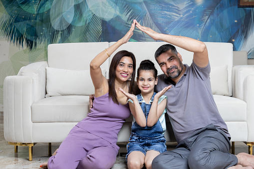 Indian family portrait making home Sign ,Home loan concept with indian family looking towards the camera