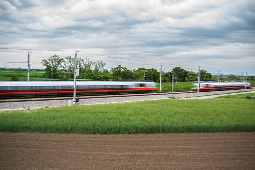 Commuter series: two high speed trains passing each other in rural landscape, therefore the trains are blurred. The green surrounding demonstrates an eco-friendly lifestyle when using public transport.