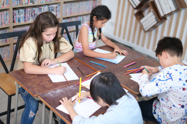 Elementary school students work together on assignments, brainstorm and collect ideas, and write them down in a book during class. Concept of education, primary school, learning and student teamwork