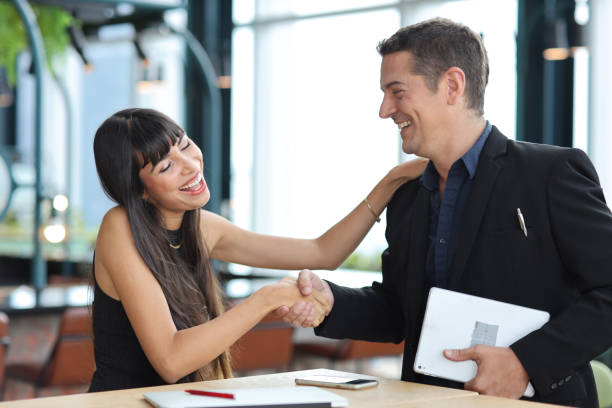 istock Collaborative process of professional businesspeople shaking hands after new business contract signed, using computer and smart mobile phone with happy face. Coworker and working together concept 1492792013