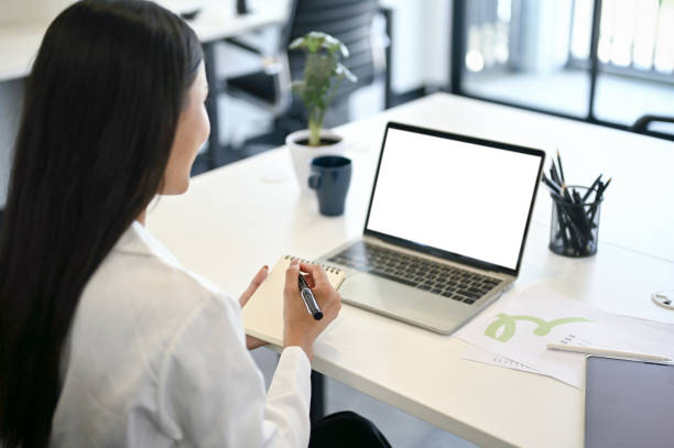 istock A businesswoman taking notes on her notebook while looking at her laptop screen 1492794373