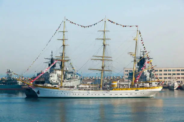 A large sailing, three-masted vessel in the Romanian harbor in Constanta, among the warships.