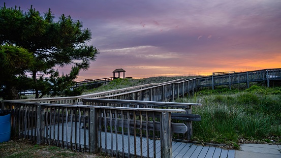 A picturesque view of a beach boardwalk at sunset in Kill Devil Hills, Outerbanks