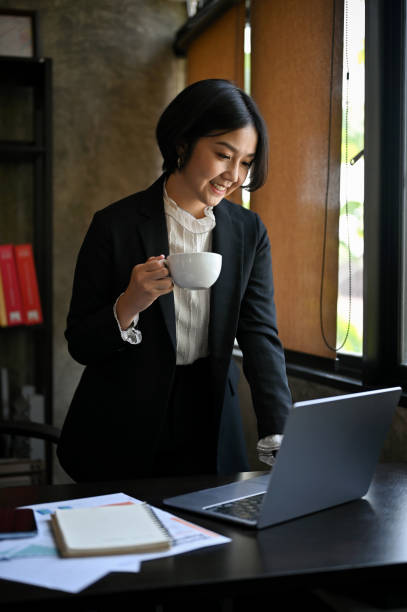 istock A businesswoman checking her work while standing and sipping coffee in her office. 1492798518