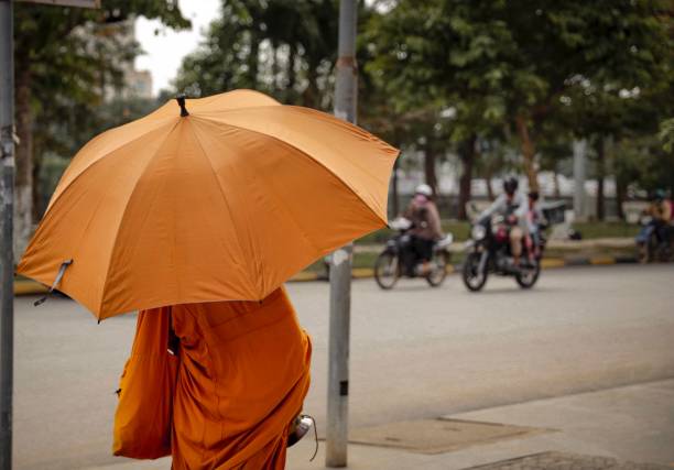 주황색 우산을 들고 승복을 입은 남자가 누군가를 기다리고 있다 - monkhood 뉴스 사진 이미지