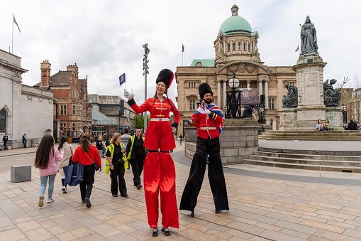 Kingston upon Hull, United Kingdom – May 06, 2023: Stilt walkers dressed up in fancy dress military costumes greet people in Kingston upon Hull, UK, on the coronation day of King Charles III