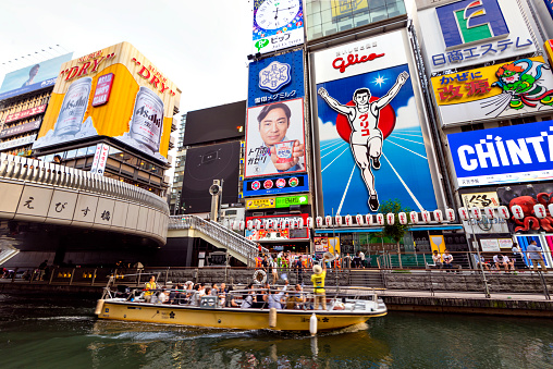 Japan - July 15, 2019 : Tourist sightseeing boat in Dotonbori canal with Colorful Advertising signs of  Shopping and Restaurants, Osaka, Kansai