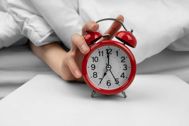 istock Woman's hand turning off red alarm clock on night table 1492800325