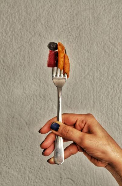 istock Vertical shot of a human hand holding a silver fork with a freshly prepared dish 1492801203